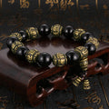 Protective black obsidian and antique brass Mala bracelet engraved with the Om Mani Padme Hum mantra.