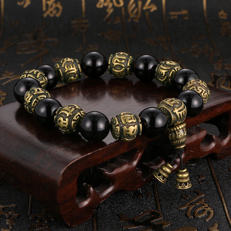 Protective black obsidian and antique brass Mala bracelet engraved with the Om Mani Padme Hum mantra.