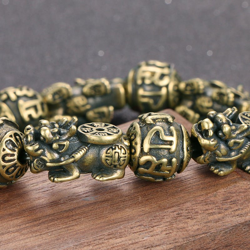 Close-up detail of the intricately carved Pi Yao charm on the solid brass wealth bracelet.