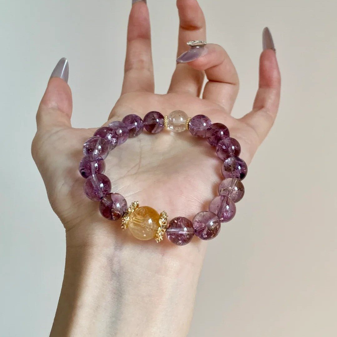 Purple Aura Quartz chakra bracelet held in hand, showcasing the white and yellow beads for balance and manifestation.