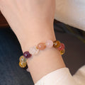 The 10MM Tiger's Eye, Amethyst, and Citrine protection and wealth bracelet worn on a wrist.