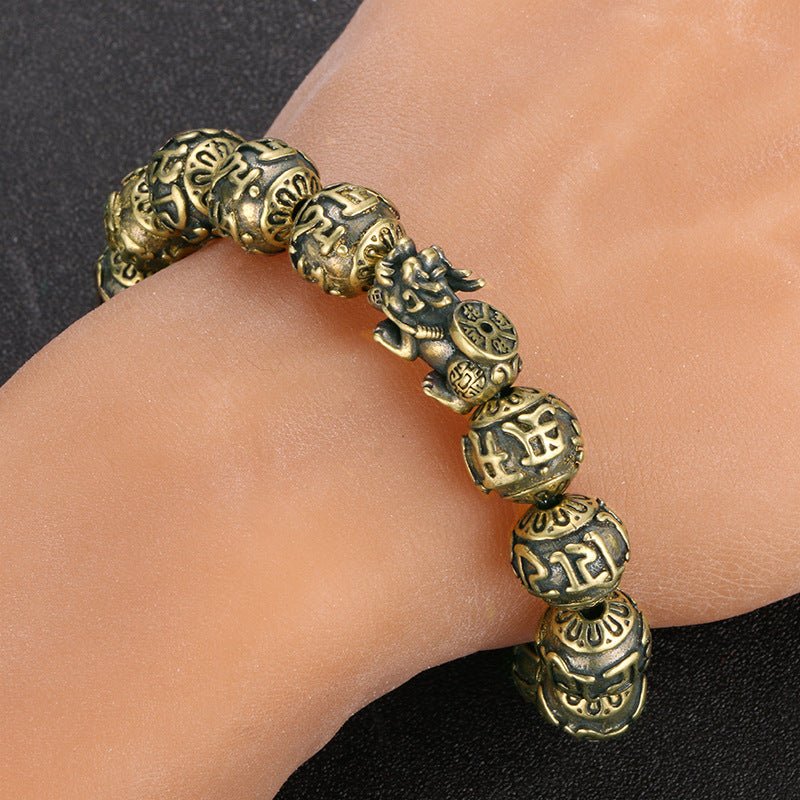 The solid brass Pi Yao wealth bracelet worn on a wrist, shown as a unisex money talisman.