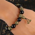 Person wearing the Om Mani Padme Hum Mala Bracelet in antique brass and black obsidian on their wrist.