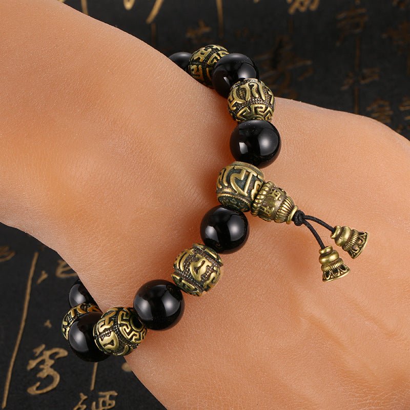 Person wearing the Om Mani Padme Hum Mala Bracelet in antique brass and black obsidian on their wrist.